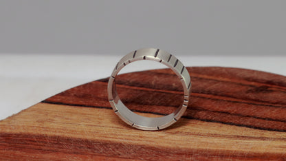 A 6mm thick silver ring band with randomly spaced black line details.