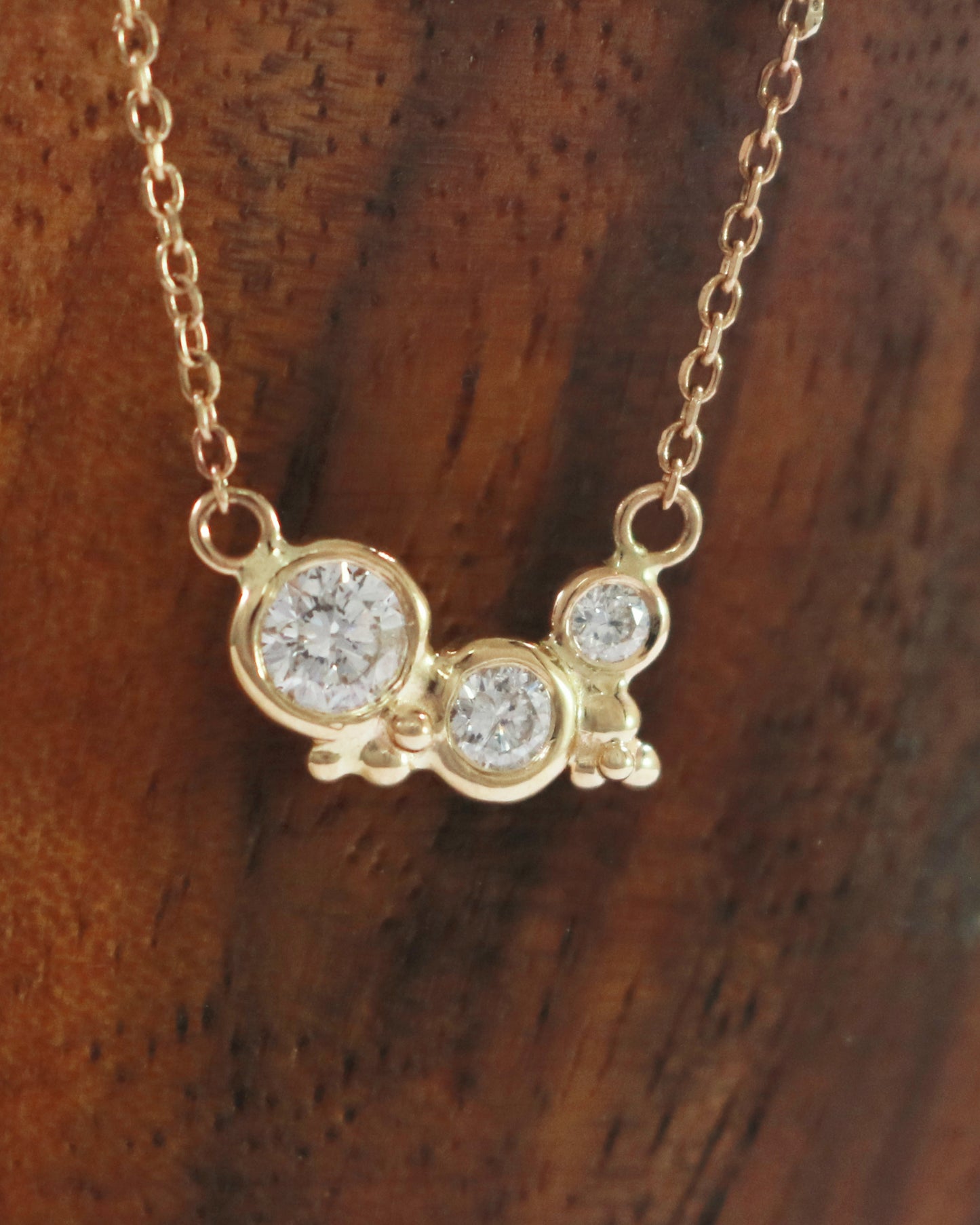 Three diamonds of descending size are set in 14k yellow gold bezels with little bubble clusters at the bottoms.