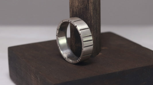 A 6mm thick silver ring band with randomly spaced black line details.