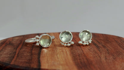 A silver ring with an 8mm round rose cut green amethyst gemstone set in sterling silver. 3 Silver bubble accents aligned along the side photographed with matching studs.