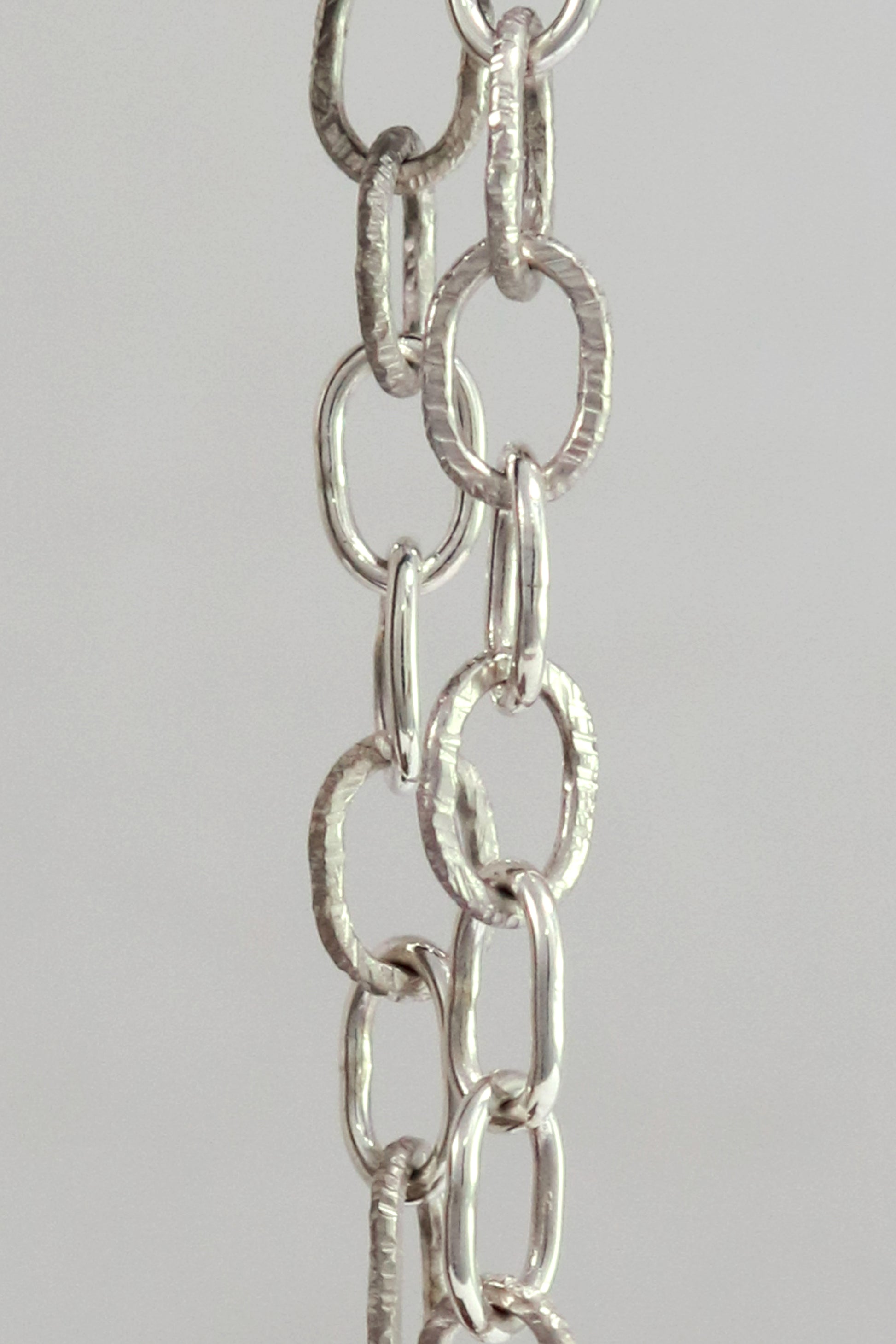 A solid sterling silver oval chain link bracelet mixed polished and textured links.