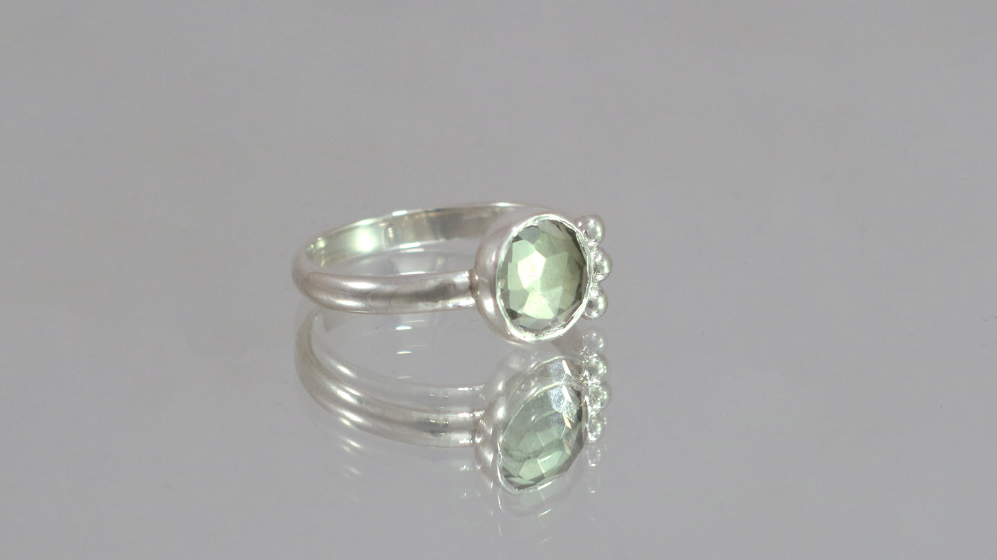 A silver ring with an 8mm round rose cut green amethyst gemstone set in sterling silver. 3 Silver bubble accents aligned along the side.