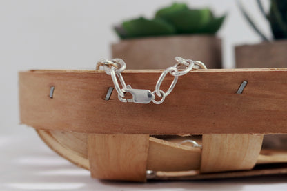 A solid sterling silver oval chain link bracelet mixed polished and textured links & a lobster claw clasp.