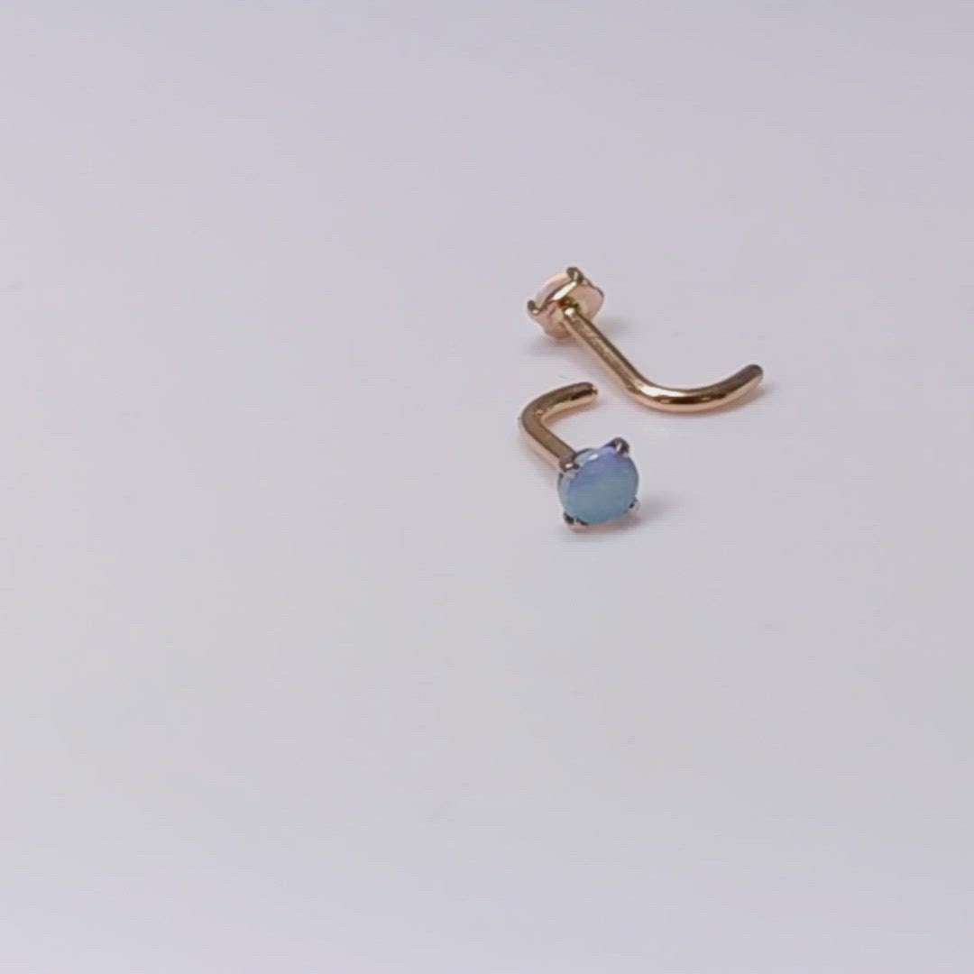 A video of 2 rose gold nose studs with blue opals set in prongs. They are spinning in one clip and moving from side to side in another clip.