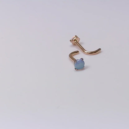 A video of 2 rose gold nose studs with blue opals set in prongs. They are spinning in one clip and moving from side to side in another clip.