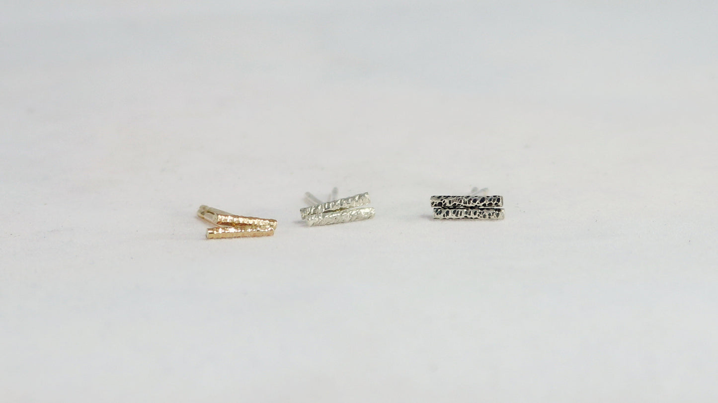 Silver and gold bar studs with a rough hammer texture.