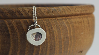 A lace agate set in sterling silver hanging from a twisted wire bale on a solid sterling silver chain.