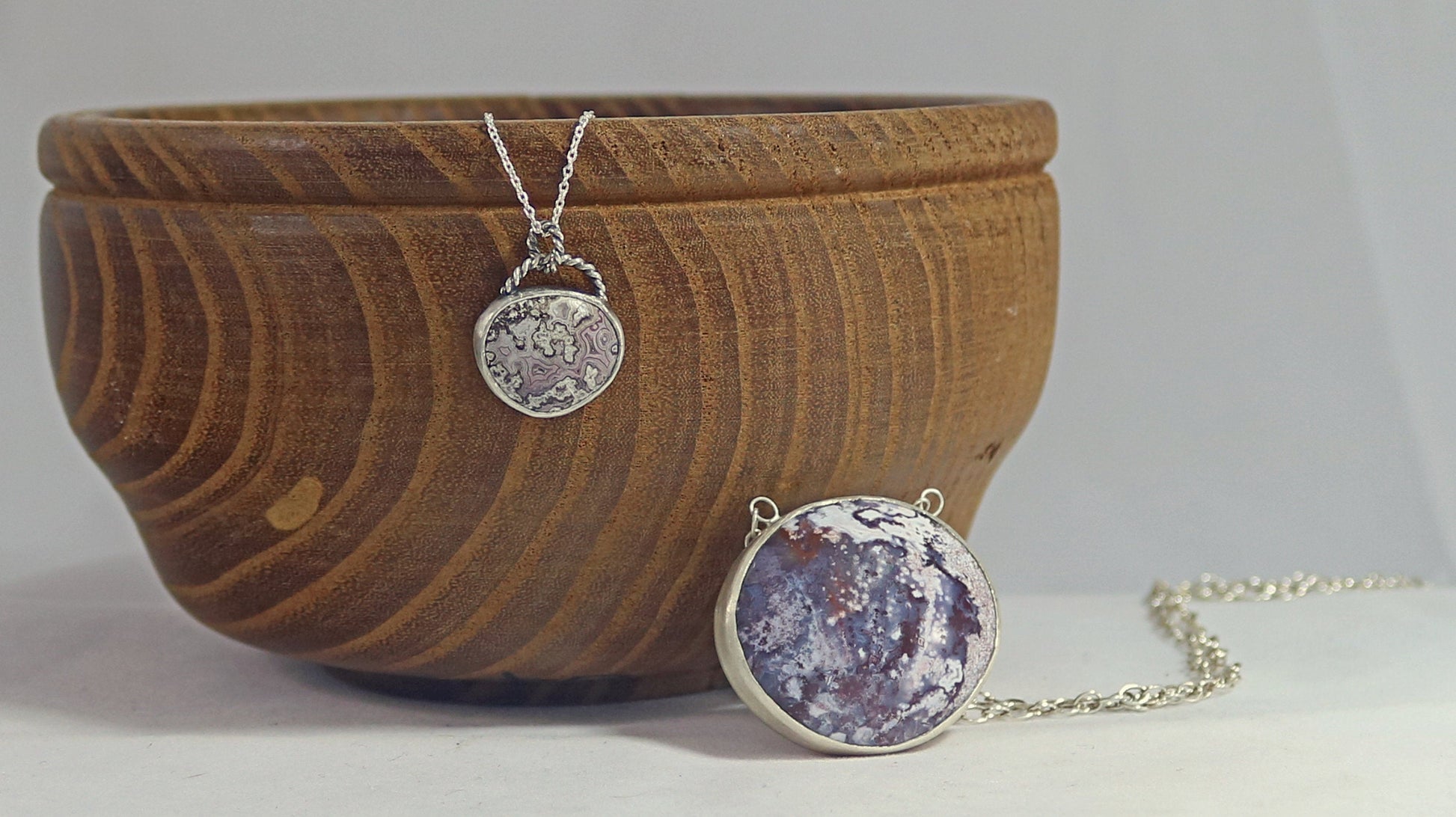 A lace agate set in sterling silver hanging from a twisted wire bale on a solid sterling silver chain.